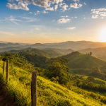 Paisagem do Sul de Minas sob céu claro e forte incidência de sol durante onda de calor