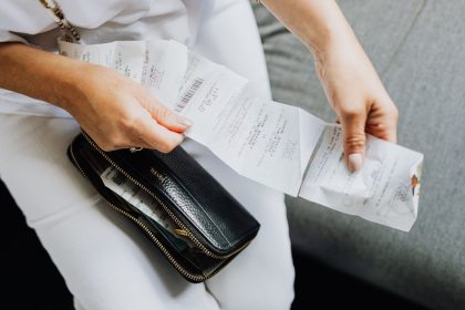 Mãos de uma mulher organizam vários recibos retirados de uma carteira preta.