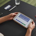 Pessoa usa um tablet em um posto de atendimento eleitoral para consultar ou registrar dados de votação.