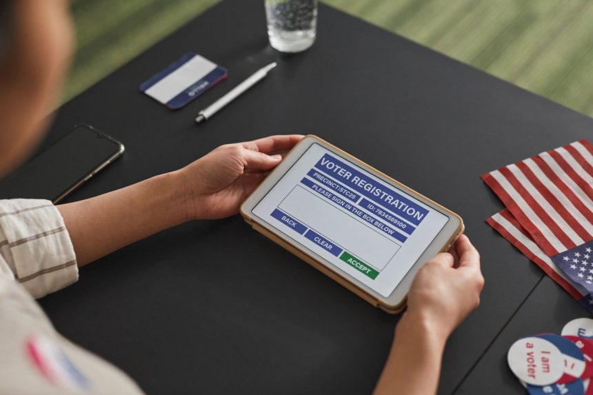 Pessoa usa um tablet em um posto de atendimento eleitoral para consultar ou registrar dados de votação.