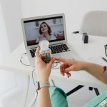 Profissional de saúde realiza atendimento médico remoto por videochamada em um computador.