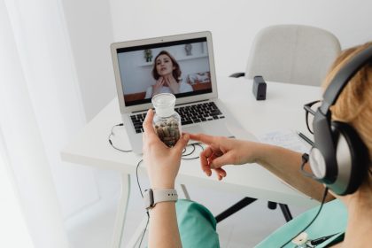 Profissional de saúde realiza atendimento médico remoto por videochamada em um computador.