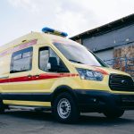 Ambulância amarela estacionada em uma área urbana.