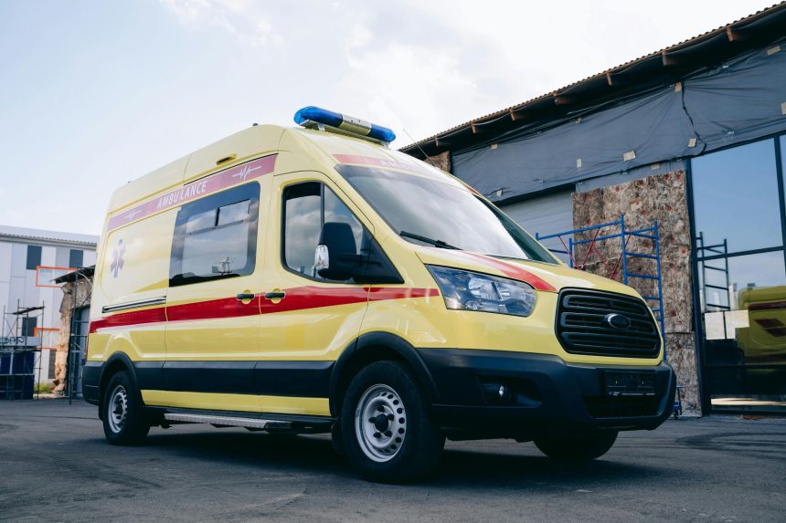 Ambulância amarela estacionada em uma área urbana.