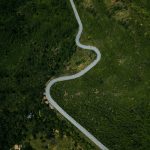 Vista aérea de uma rodovia sinuosa entre áreas de vegetação verde em Minas Gerais.