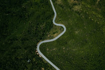Vista aérea de uma rodovia sinuosa entre áreas de vegetação verde em Minas Gerais.