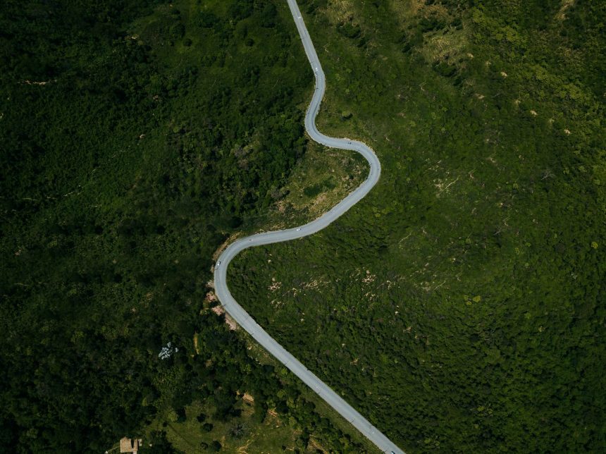 Vista aérea de uma rodovia sinuosa entre áreas de vegetação verde em Minas Gerais.
