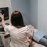 Médica realiza exame de ultrassonografia em uma paciente em consultório.