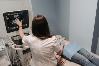 Médica realiza exame de ultrassonografia em uma paciente em consultório.