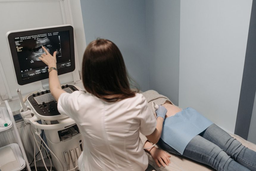 Médica realiza exame de ultrassonografia em uma paciente em consultório.