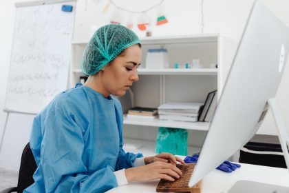 Profissional da saúde trabalha diante de um computador em um ambiente de laboratório.