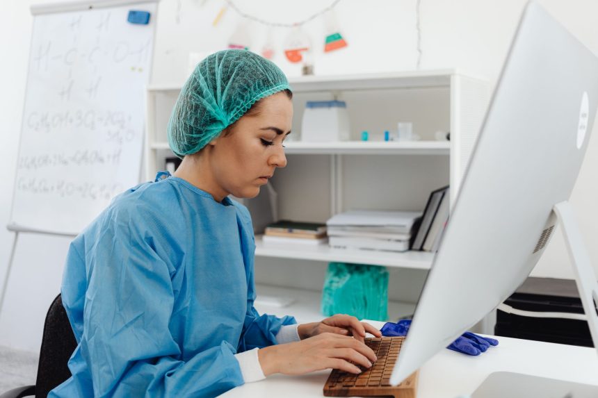 Profissional da saúde trabalha diante de um computador em um ambiente de laboratório.
