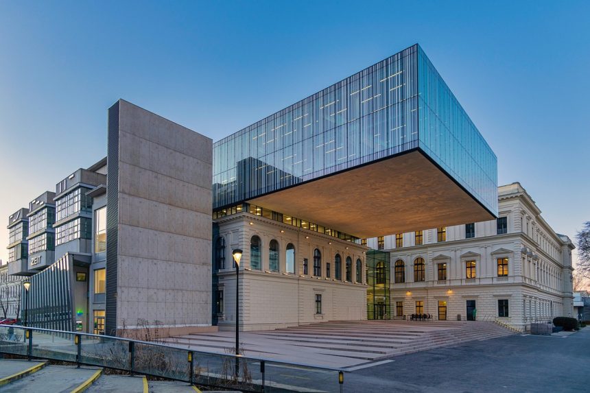 Fachada de um edifício universitário moderno, com amplas janelas e área arborizada à frente