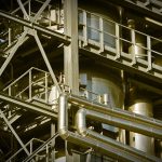 Vista de uma planta industrial com grandes estruturas metálicas e instalações de produção.