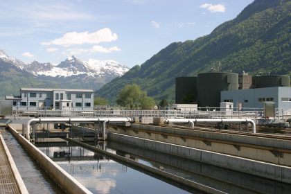 Tanques circulares de uma estação de tratamento de esgoto cercados por vegetação.