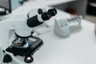Microscópio em destaque sobre a bancada de um laboratório científico
