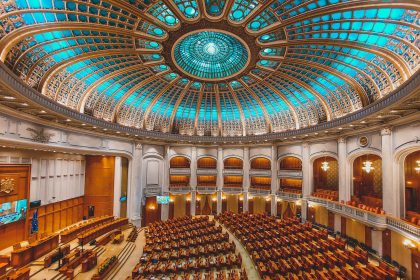 Plenário legislativo com assentos dispostos em semicírculo sob uma cúpula ornamentada.