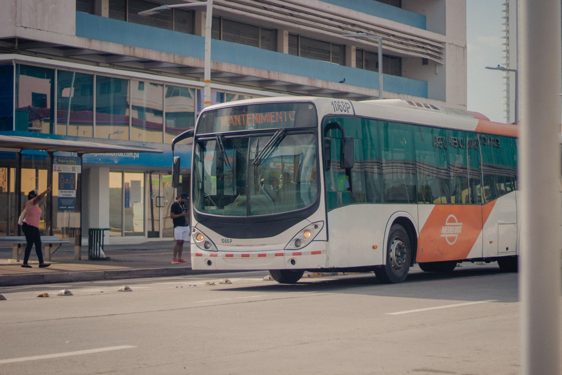 Ônibus urbano parado em um ponto enquanto passageiros embarcam.