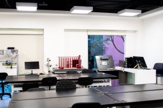 Interior de laboratório educacional contemporâneo, com mesas e equipamentos para atividades de ensino e pesquisa.