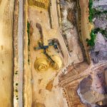 Vista aérea de uma mina a céu aberto, com máquinas e vias de circulação cercadas por áreas de vegetação.